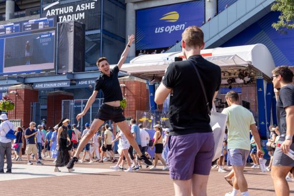 A tennis fan jumps for a photo at the Open.