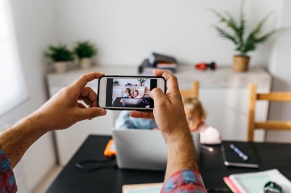 A man taking photos of his children using a laptop 