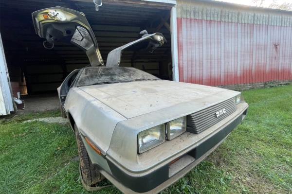 A 1981 gull-winged DeLorean sits outside a bar with its doors popped open. 