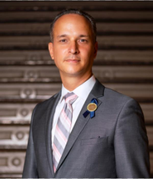 dist 14 superintendent david cintron, in a suit against abackdrop of a me<em></em>tallic rolling garage door, staring at the camera;