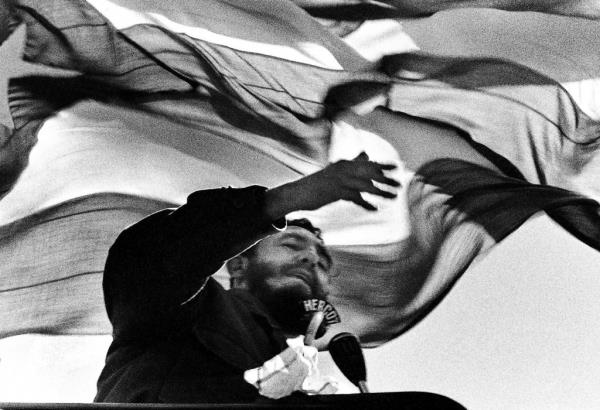 Fidel Castro speaking behind a podium in 1972, in Chile, with a flag in the background.
