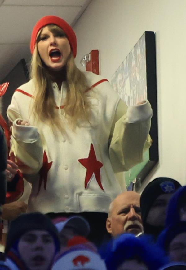 Taylor Swift, in a red hat and white Chiefs jacket cheers on the Kansas City Chiefs.