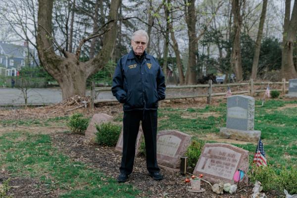 Father Michael Drury stands next to the tombstone of baby Mary