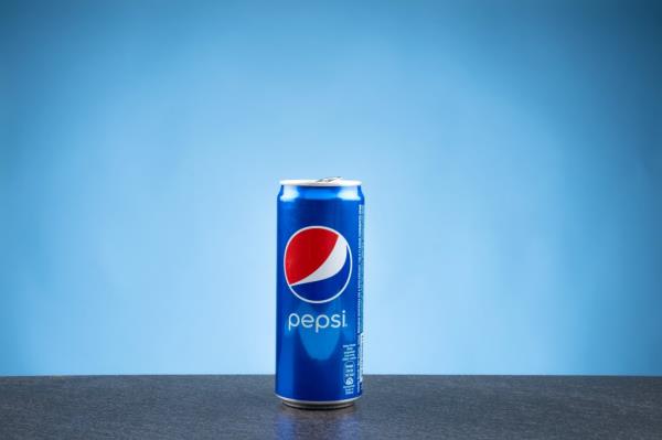 A can of Pepsi on a flat surface against a blue backdrop.