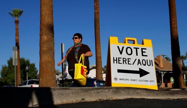 A woman walks past a sign directing voters to a polling place in the Phoenix, Arizona in this file photo taken November 2, 2010.