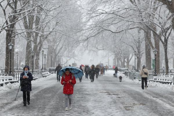 People walk through the falling snow in Central Park on February 13, 2024 in New York City. 