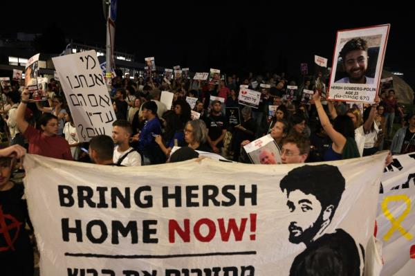 Relatives and supporters raise placards and deploy a banner bearing portraits of Israeli hostage Hersh Goldberg-Polin