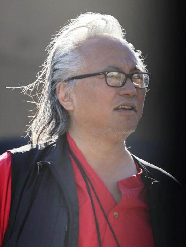 Iwamasa's stringy, gray hair is slicked back. He wears reading glasses in a close up shot of his face