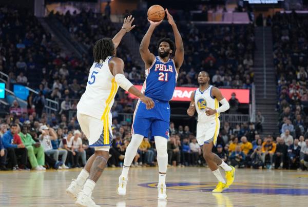 Joel Embiid #21 of the Philadelphia 76ers shoots a three-point shot over Kevon Loo<em></em>ney #5 of the Golden State Warriors during the first quarter at Chase Center on January 30, 2024 in San Francisco, California.  