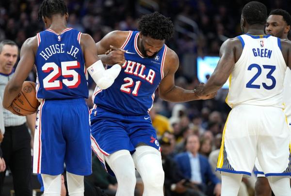 Joel Embiid #21 of the Philadelphia 76ers gets helped up from the floor by teammate Danuel House Jr. #25 and Draymond Green #23 of the Golden State Warriors during the second quarter at Chase Center on January 30, 2024 in San Francisco, California.  