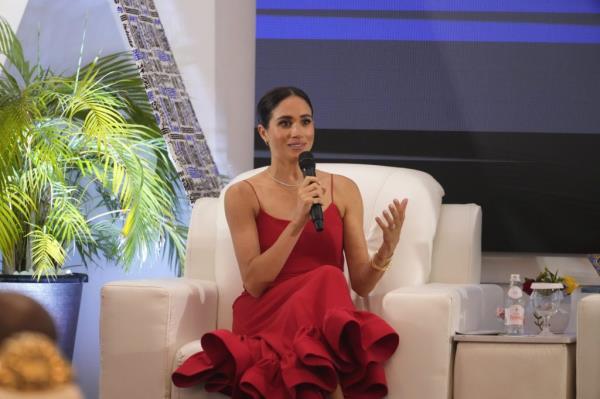 Meghan, the Duchess of Sussex, speaking at an event in Abuja, Nigeria, in a red dress while holding a microphone