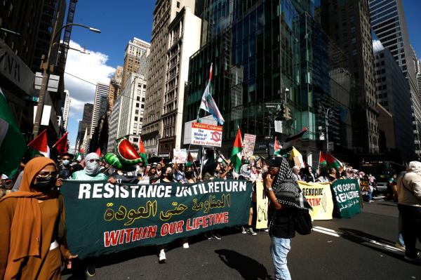 Demo<em></em>nstrators marching through the streets of New York City with signs and Palestinian flags in protest of the co<em></em>nflict in Gaza.