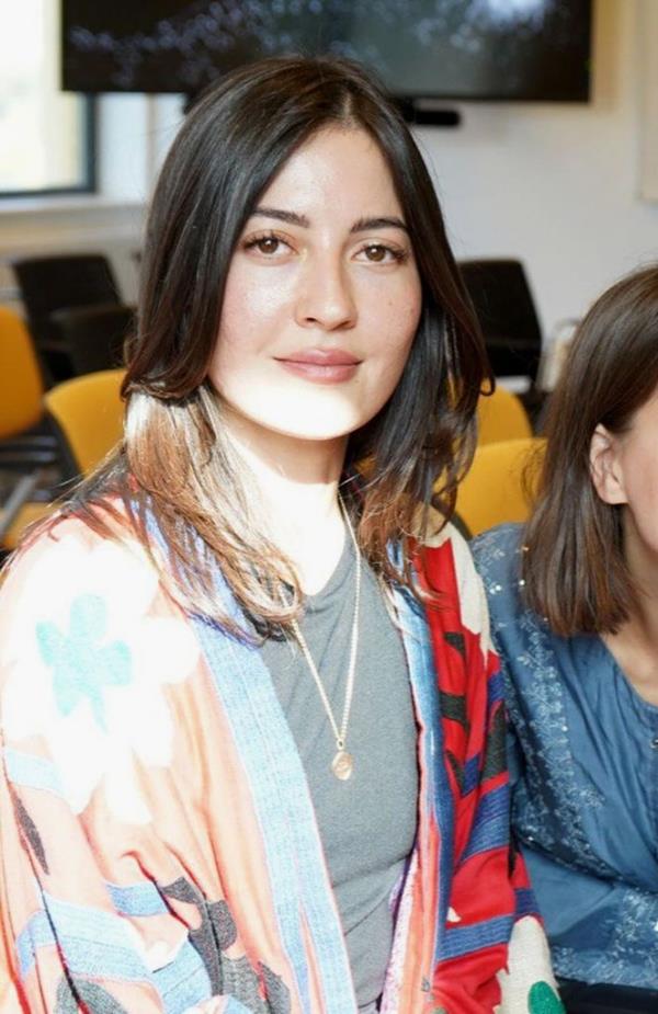 A photo of Sabina Rosas, a woman with long brown hair wearing a kimono-style top over a gray t-shirt.