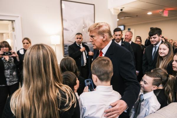 Former President Do<em></em>nald Trump co<em></em>nversing with young attendees at the wake of NYPD officer Jo<em></em>nathan Diller