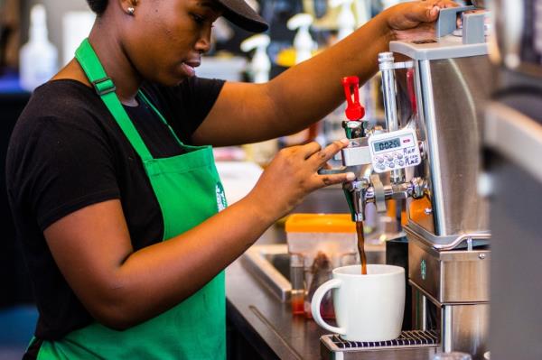 Starbucks barista prepares cup of coffee for customer.