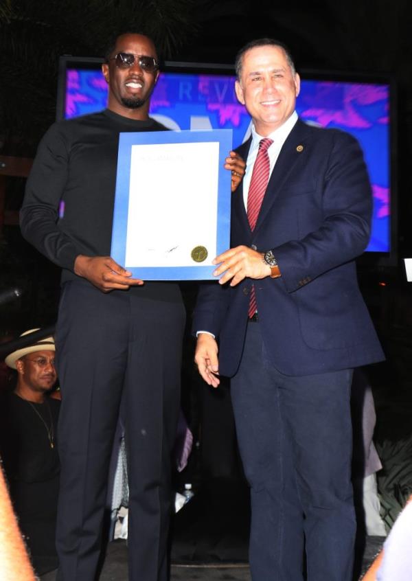 Sean 'Diddy' Combs and former Mayor of Miami Beach, Philip Levine, on stage holding a piece of paper at the 2016 REVOLT Music Conference