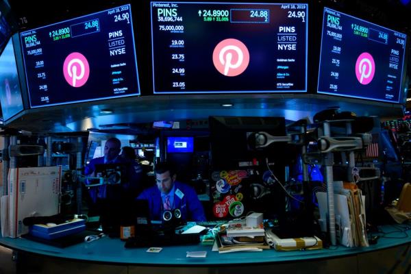 Traders working at NYSE with Pinterest logo displayed on screens during company's IPO.