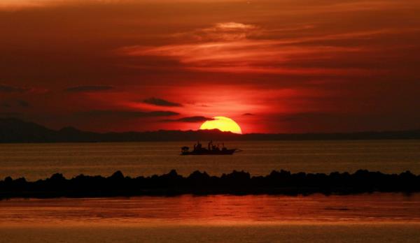Residents fishing on a motorboat at sunset in the waters of Mogpog town, Marinduque island, south of Manila