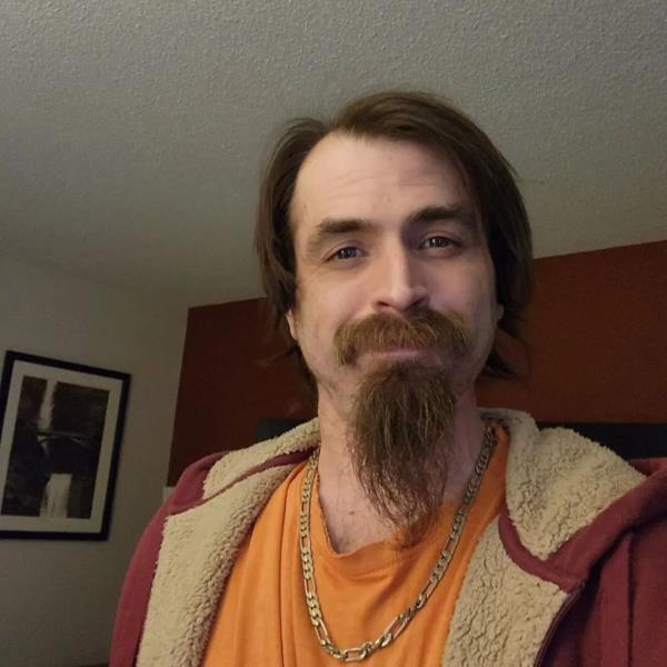 Man with beard and mustache wearing a red jacket and gold chain, presumably Robert Schock, in North Cascades Natio<em></em>nal Park