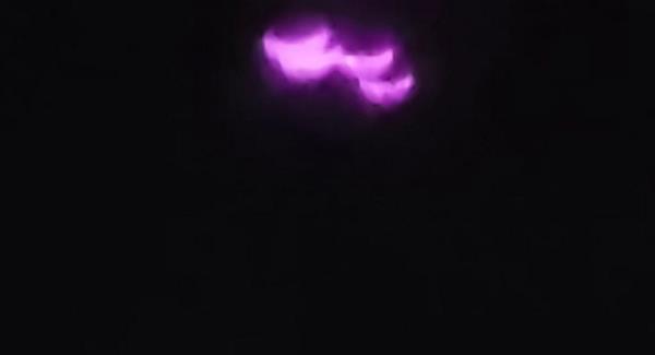 Four unusually shaped pink orbs bl<em></em>inked clearly against the dark nighttime sky, distinctly separate from the cityscape down below.