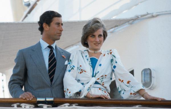 A photo of Princes Charles and Diana, who is smiling, clad in a silk, floral dress, on board the Royal yacht Britannia.