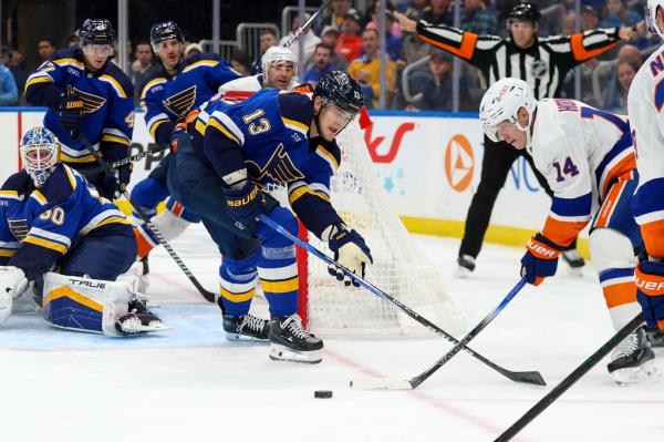 St. Louis Blues' Alexey Toropchenko and New York Islanders' Bo Horvat reach for the puck during an NHL game.