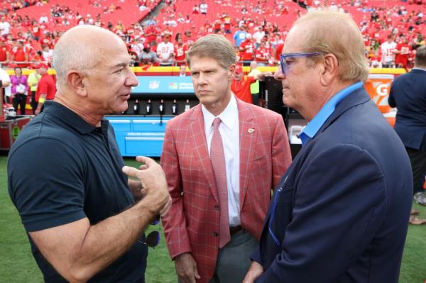 Bezos on the Chiefs football field talking with Kansas City Chiefs Owner Clark Hunt and Los Angeles Chargers Owner Dean Spanos.