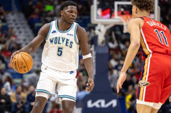 Minnesota Timberwolves guard Anthony Edwards  brings the ball up court against New Orleans Pelicans guard Dyson Daniels.