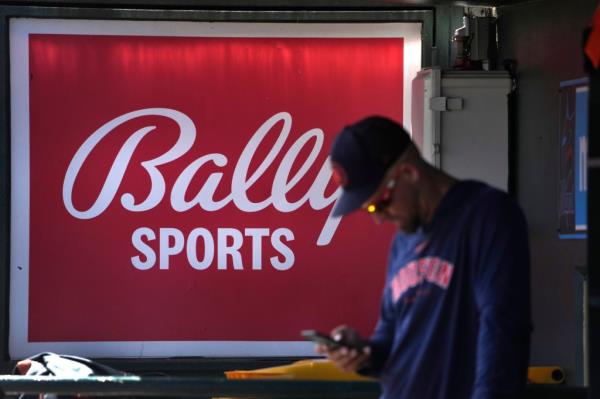 A member of the Houston Astros stands in the dugout in front of a Bally Sports sign before the team's spring training ba<em></em>seball game against the St. Louis Cardinals.