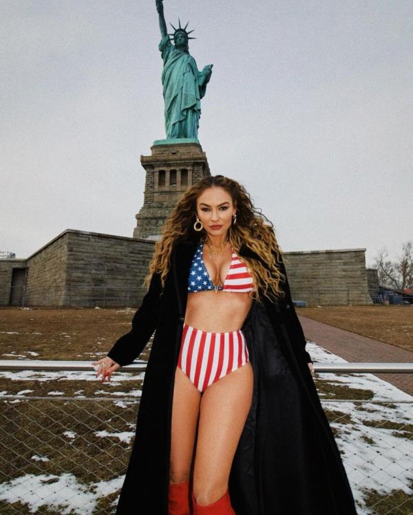 Drea de Matteo posing in front of a statue of Alexander the Great, in a garment and a coat