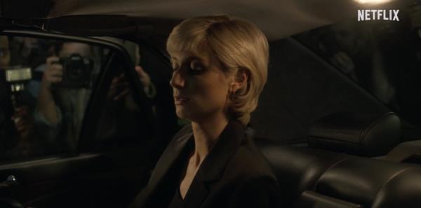 Princess Diana (Elizabeth Debicki) sitting in a car with photographers taking photos of her. 