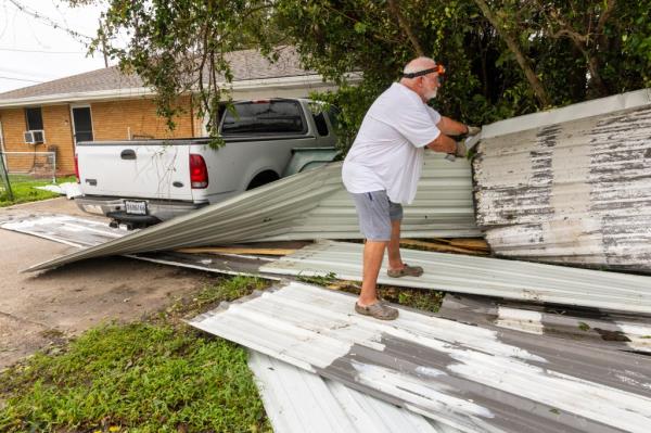 Rick Armstrong removes me<em></em>tal roofing that flew from a restaurant a<em></em>bout a block from his house and o<em></em>nto his truck in his driveway during Hurricane Francine on Thursday, Sept. 12, 2024 in Houma, La. 