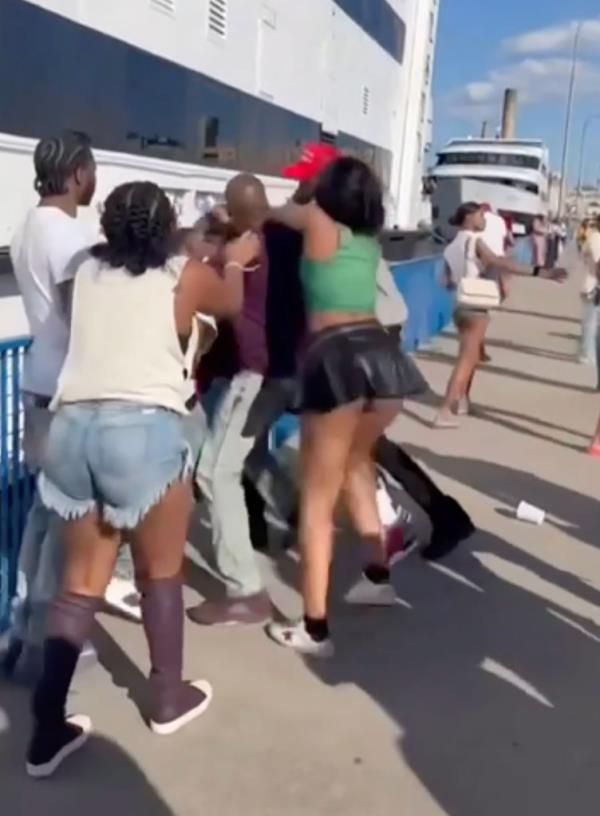 Several men and women can be seen pushing and shoving each other on the pier right next to the massive yacht. 