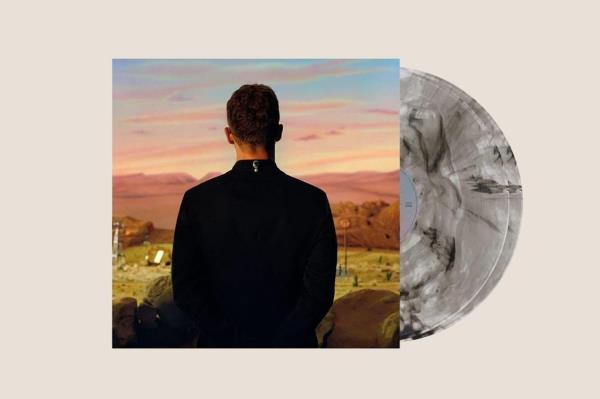 A man standing in front of an Amazon Exclusive Vinyl record titled 'Everything I Thought It Was', priced at $35.98