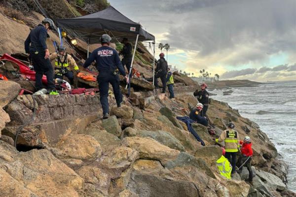 Rescuers stand on the cliff.