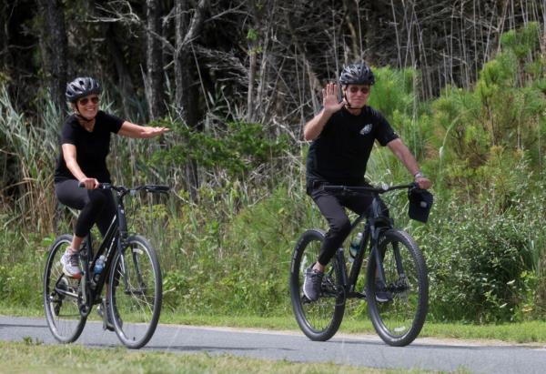 U.S. President Joe Biden and first lady Jill Biden wave as they ride bikes down a path in Gordons Pond State Park in Rehoboth Beach, Delaware, U.S., July 31, 2023. 