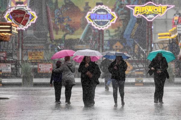 People shielding themselves from heavy ran at a funfair in Germany.