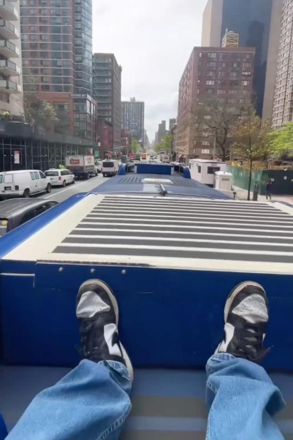 Screenshot of a video of a person lying down atop a bus