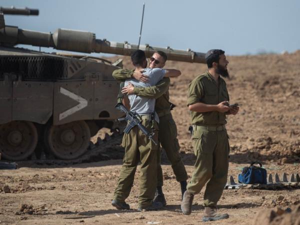 Israeli soldiers meet up and embrace at a ba<em></em>se in southern Israel wher<em></em>e tank repairs are being carried out near the border with the Gaza Strip on November 23, 2023. Tomorrow, on November 24, Israel and Hamas are due to begin a ceasefire and exchange 50 Israeli hostages for 150 Palestinians priso<em></em>ners held in Israel. The ceasefire is due to last five days with a<em></em>bout 12 hostages released each day.