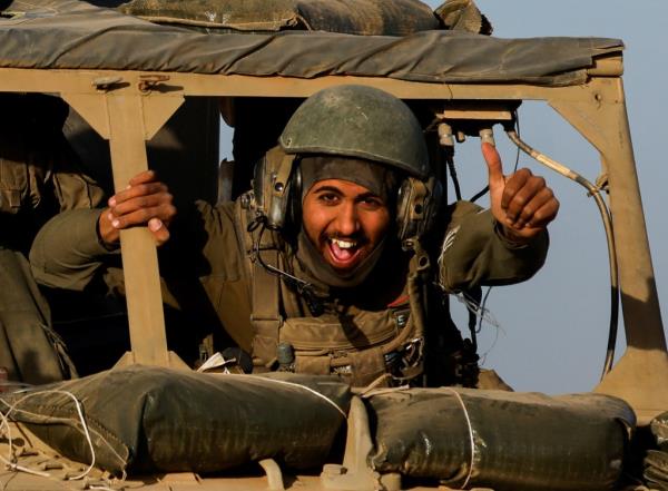 An Israeli soldier gestures from a military vehicle while driving by Israel's border after leaving Gaza during the temporary truce between the Palestinian Islamist group Hamas and Israel, in Israel, Nov. 24, 2023. 