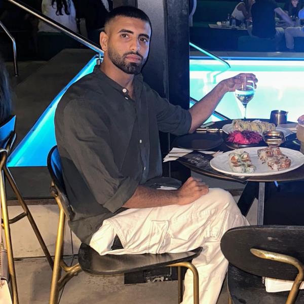 A photo of Raz Peri at a table in a restaurant with a glass of wine in his hand.