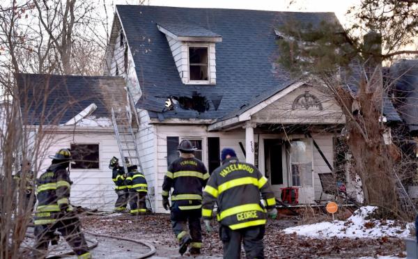Firefighters stand outside a burnt house as they pick up their equipment after extinguishing a fire in Ferguson, Missouri, suspected of being suspicious.