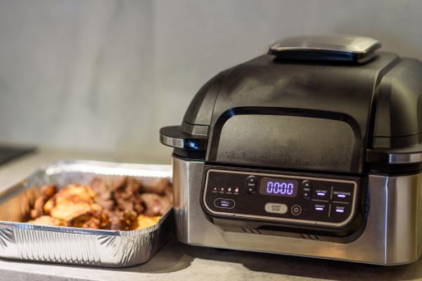 A tray of meat next to an air fryer
