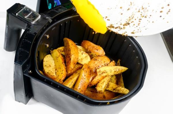 An air fryer with potato wedges inside