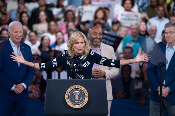 First Lady Jill Biden, with the word 'VOTE' printed on her dress, speaking at a podium during a post-debate campaign rally in Raleigh, North Carolina