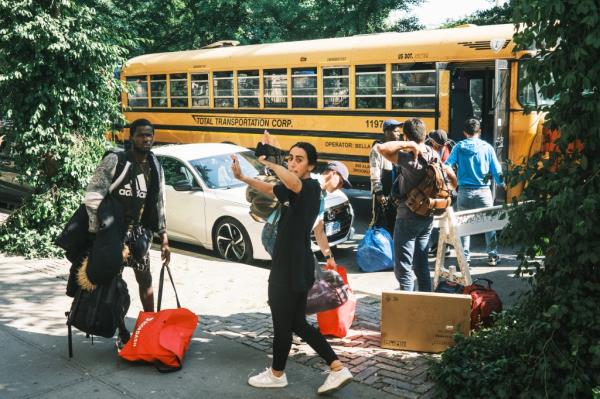 Migrants get off a school bus