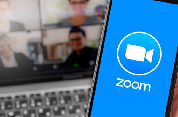 Zoom logo on the screen smartphone with notebook blurred background closeup. Zoom Video Communications is a company that provides remote co<em></em>nferencing services. Moscow, Russia - April 1, 2020