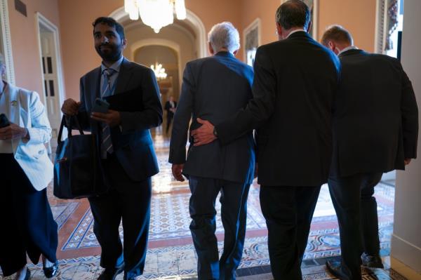 Senate Minority Leader Mitch McConnell, R-Ky., center, is assisted by Sen. John Barrasso, R-Wyo., second from right, and a Capitol Police officer after the 81-year-old GOP leader froze at the micropho<em></em>nes as he arrived for a news co<em></em>nference at the Capitol in Washington, Wednesday, July 26, 2023. 
