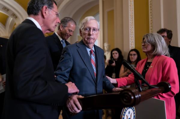 Senate Minority Leader Mitch McConnell, R-Ky., center, is helped by, from left, Sen. John Barrasso, R-Wyo., Sen. John Thune, R-S.D., and Sen. Joni Ernst, R-Iowa, after the 81-year-old GOP leader froze at the micropho<em></em>nes as he arrived for a news conference, at the Capitol in Washington, Wednesday, July 26, 2023. 