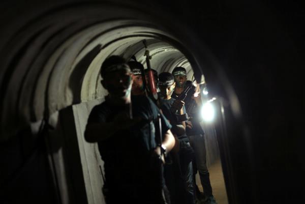 Young Palestinians holding weapons walk in a tunnel during a military exercise graduation ceremony at a summer camp organized by Hamas's armed wing, east of Gaza City. 